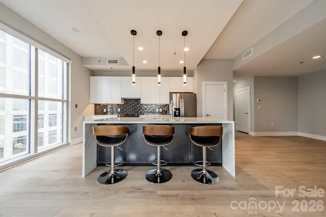 a room with stainless steel appliances kitchen island granite countertop a table chairs in it and wooden floors