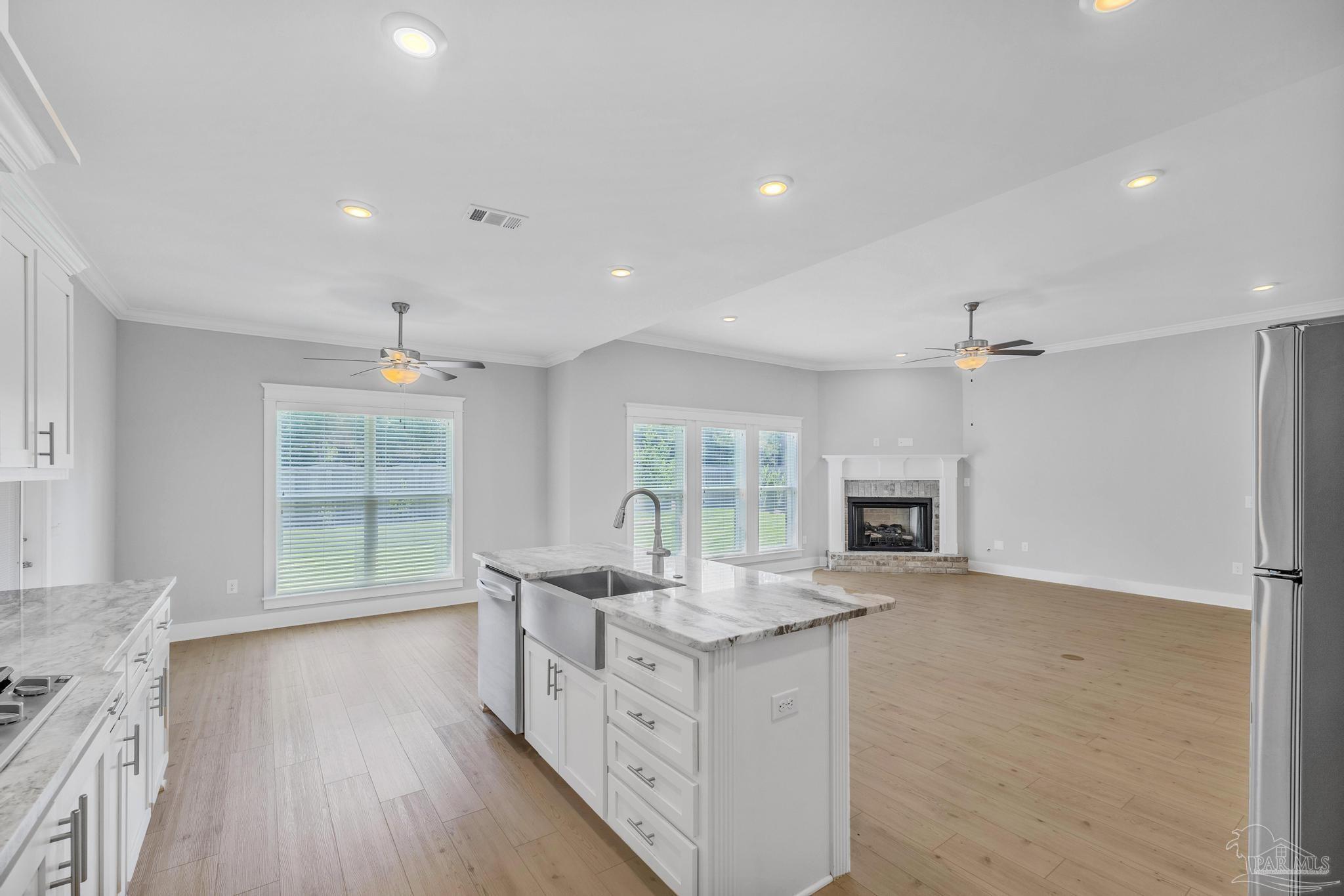 6264 Howie Way Pace, FL 32571 - Photo 12 of 42 a open kitchen with granite countertop a stove top oven a sink a dining table and chairs with wooden floor
