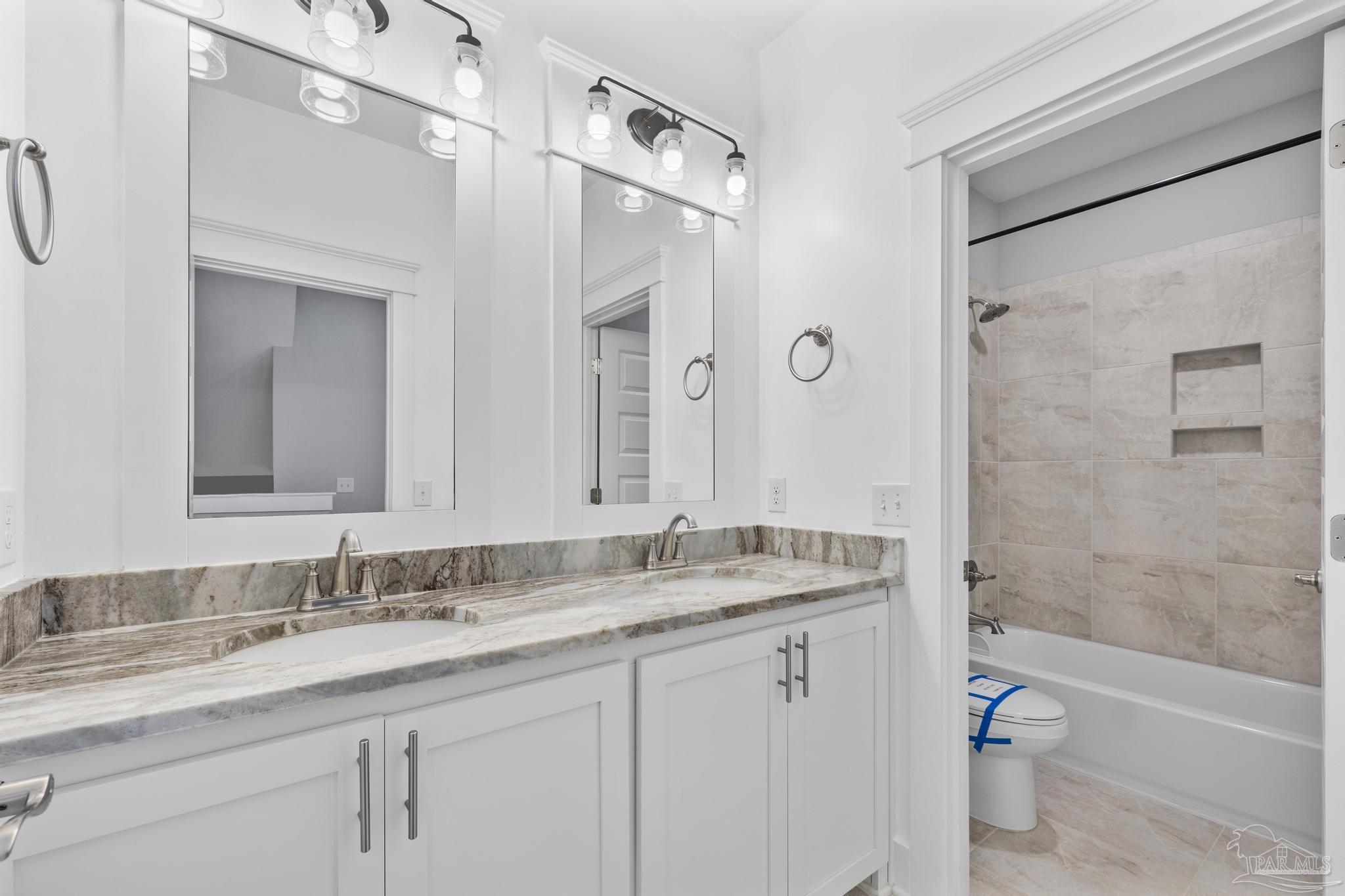 6264 Howie Way Pace, FL 32571 - Photo 21 of 42 a bathroom with a granite countertop sink a toilet a mirror and shower