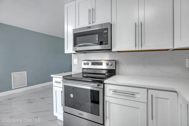 a kitchen with cabinets stainless steel appliances and wooden floor