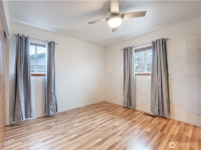 a view of empty room with wooden floor and fan