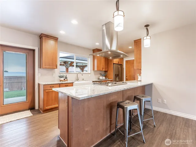 a large kitchen with stainless steel appliances kitchen island a large counter space a sink and a wooden floors