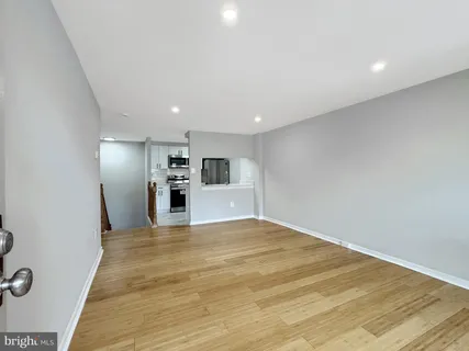 a view of an empty room with wooden floor and windows