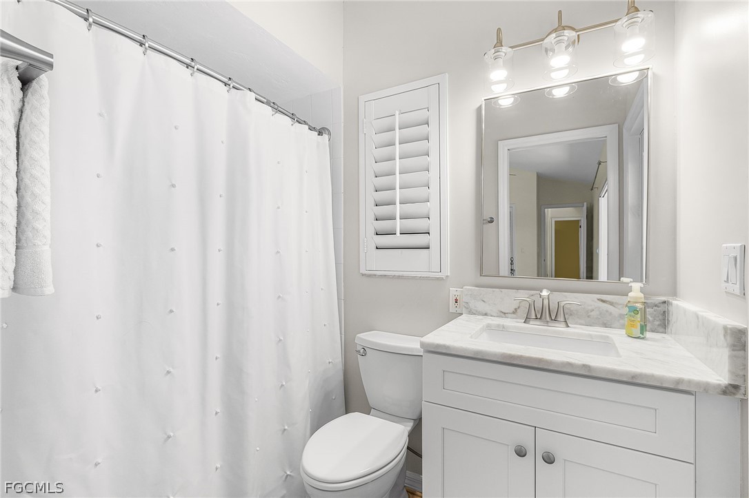 7747 Grande Pine Road Bokeelia, FL 33922 - Photo 29 of 45 a bathroom with a sink a toilet and shower curtain