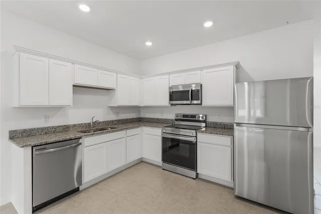 a kitchen with stainless steel appliances granite countertop a stove a sink and a refrigerator