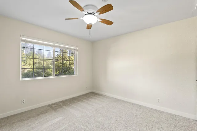 an empty room with a window and a fan