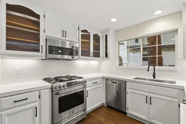 a kitchen with cabinets stainless steel appliances a sink and a window