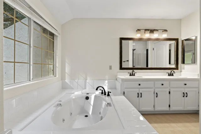 a bathroom with a double vanity sink mirror and bathtub
