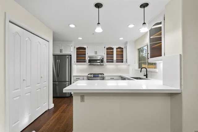 a kitchen with stainless steel appliances granite countertop a sink refrigerator and cabinets