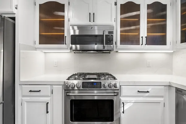 a stove top oven sitting inside of a kitchen with stainless steel appliances wooden floor and a sink