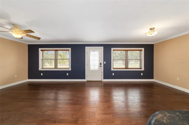 a view of an empty room with a window and wooden floor