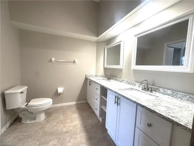 a bathroom with a granite countertop sink a toilet and a mirror