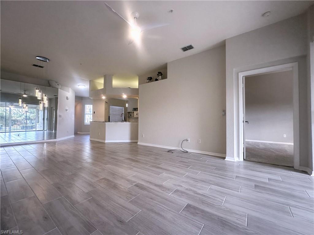 6922 Satinleaf Road North, Unit 203 Naples, FL 34109 - Photo 7 of 31 an empty room with wooden floor and windows
