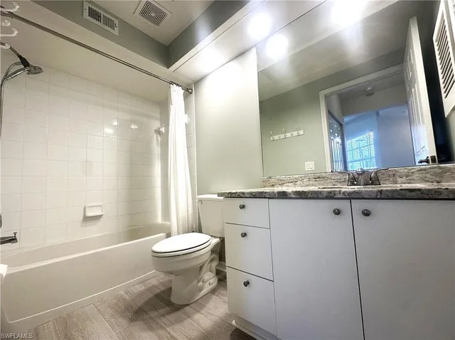 a bathroom with a granite countertop sink a toilet a mirror and bathtub
