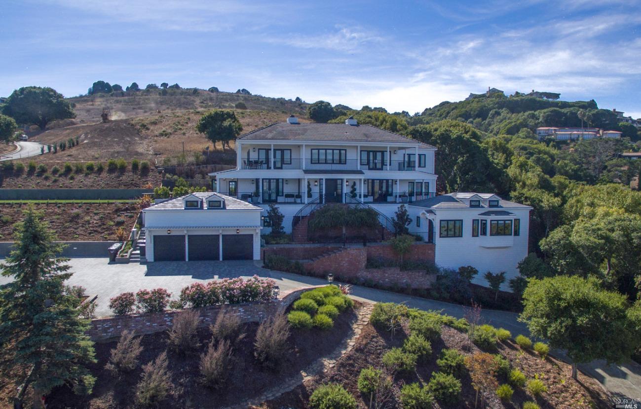 a front view of a house with a yard and mountain view in back