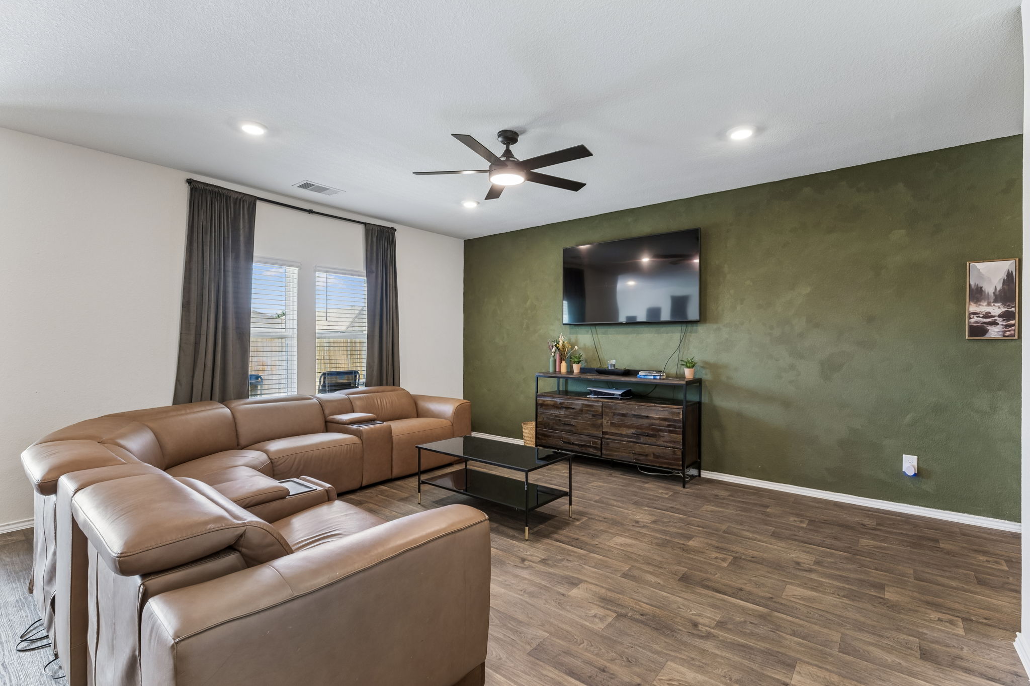 343 Sickle Loop Kyle, TX 78640 - Photo 11 of 40 Living area featuring wood-finish flooring, a contemporary ceiling fan with integrated lighting, recessed ceiling lights, a prominent accent wall, and dual windows equipped with blinds