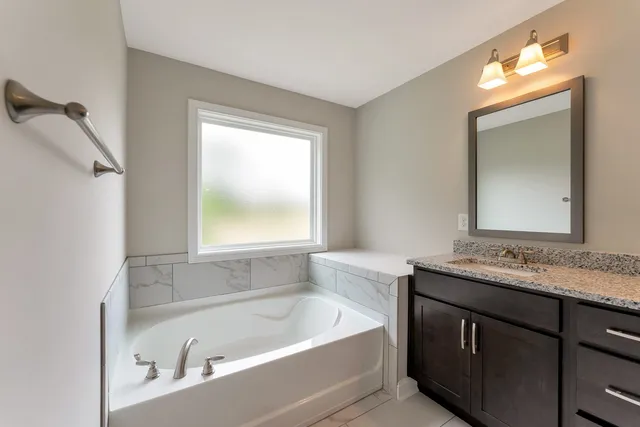 a bathroom with a tub a sink and a window