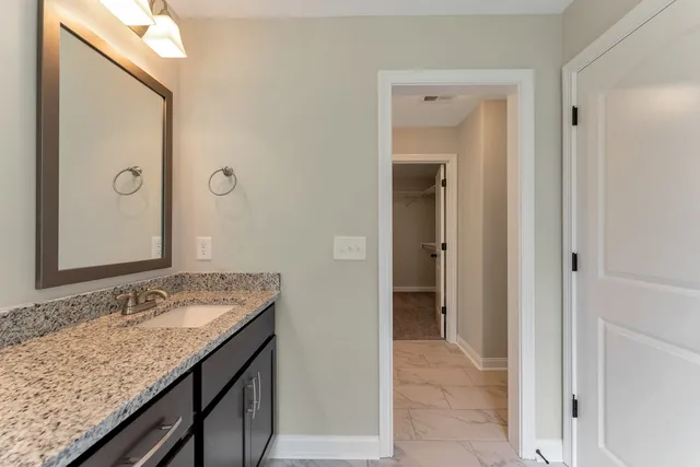 a bathroom with a granite countertop sink and a mirror