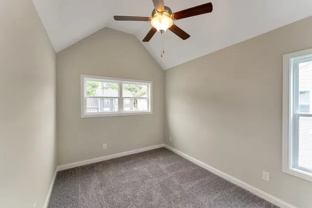 an empty room with windows and fan