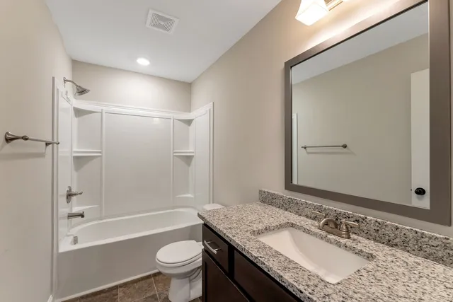 a bathroom with a granite countertop sink a toilet and shower