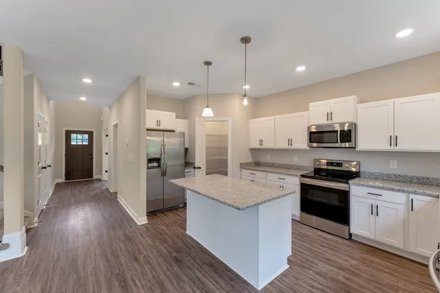 a large kitchen with stainless steel appliances granite countertop a stove and a refrigerator