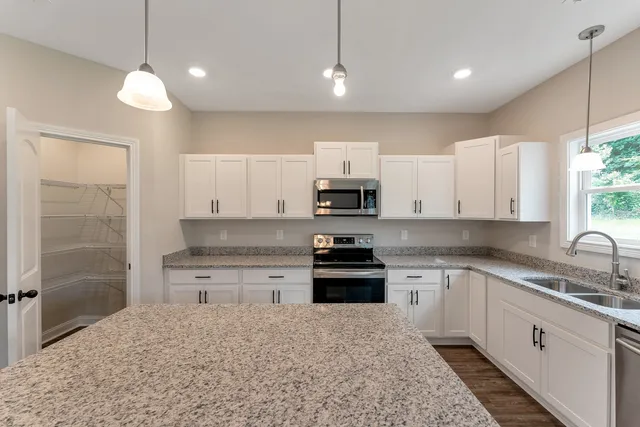 a kitchen with stainless steel appliances granite countertop a sink a stove a refrigerator and cabinets