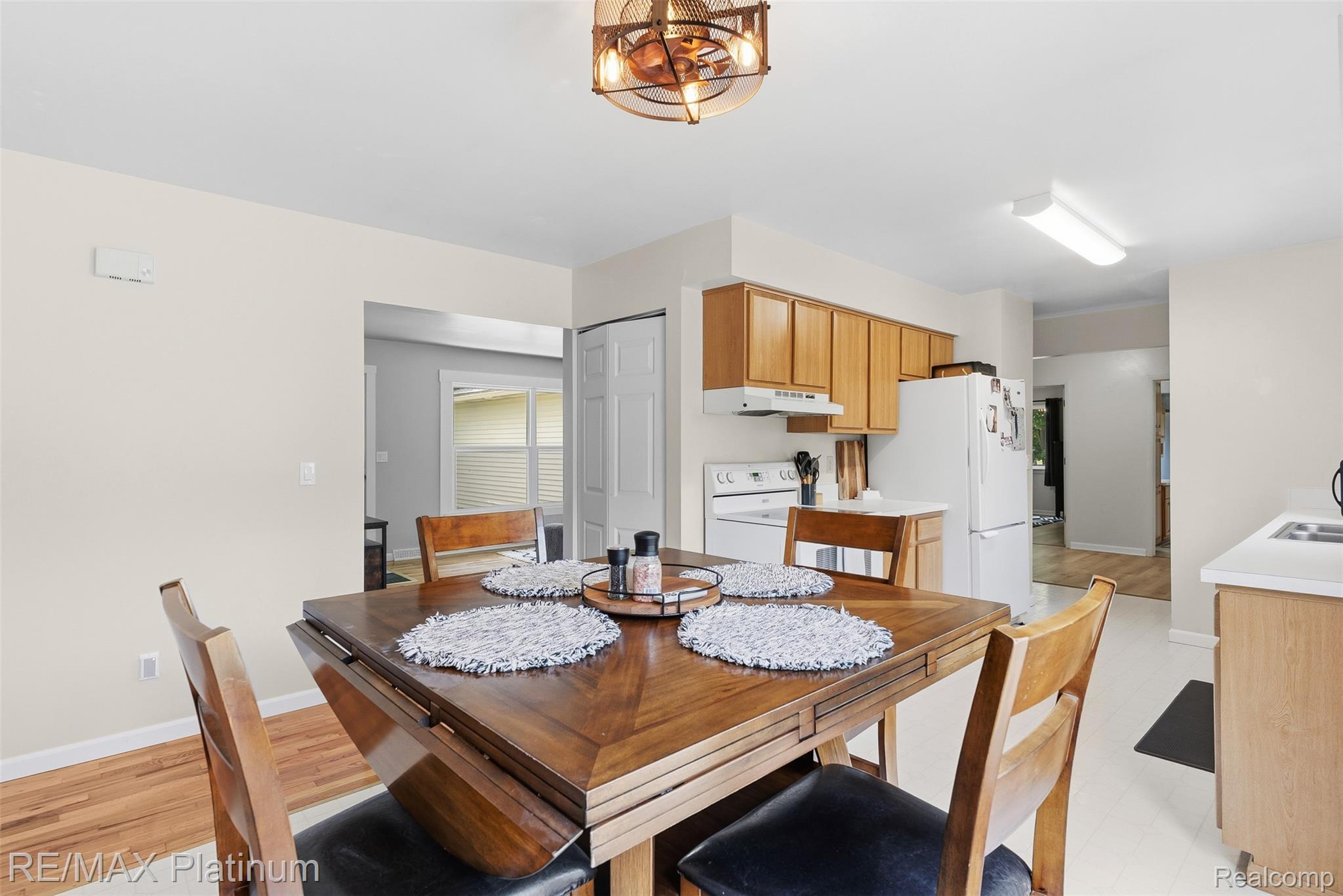 8370 West Rolston Road Linden, MI 48451 - Photo 10 of 36 Dining area featuring a wood-finish table with drop-leaf extensions, an overhead bronze-tone light fixture, and wood-finish flooring extending into an adjacent room