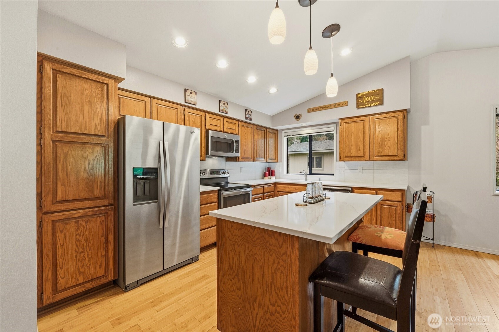 6830 Norma Beach Road Edmonds, WA 98026 - Photo 8 of 30 a kitchen with stainless steel appliances granite countertop a refrigerator a sink a stove a dining table and chairs with wooden floor