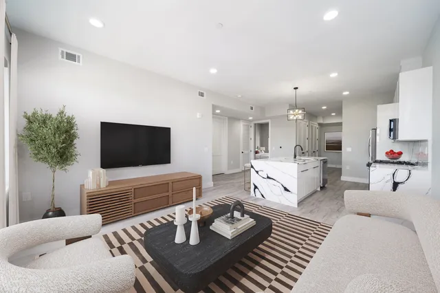 a living room with furniture kitchen view and a flat screen tv