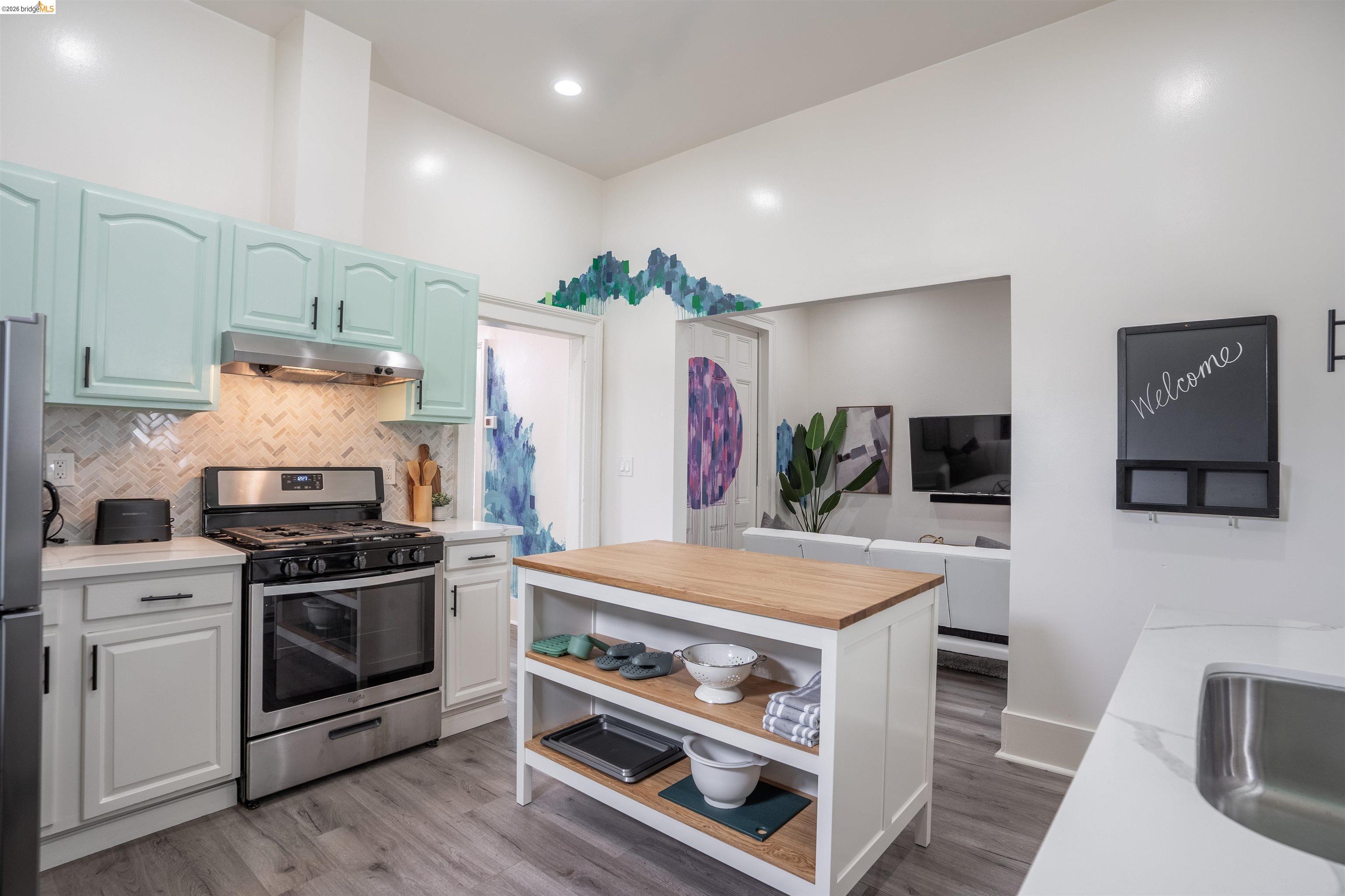 527 Chester Street Oakland, CA 94607 - Photo 38 of 47 527 (Upstairs) Kitchen with stainless steel appliances, open shelves, light wood-style flooring, light stone counters, and recessed lighting