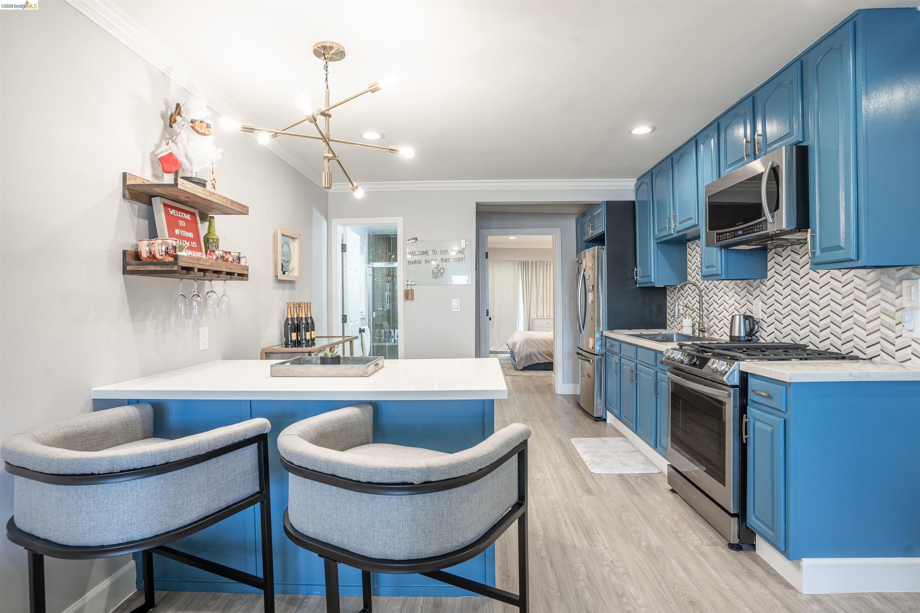 527 Chester Street Oakland, CA 94607 - Photo 8 of 47 525 (Downstairs) Kitchen with blue cabinetry, a kitchen bar, a peninsula, stainless steel appliances, and a chandelier