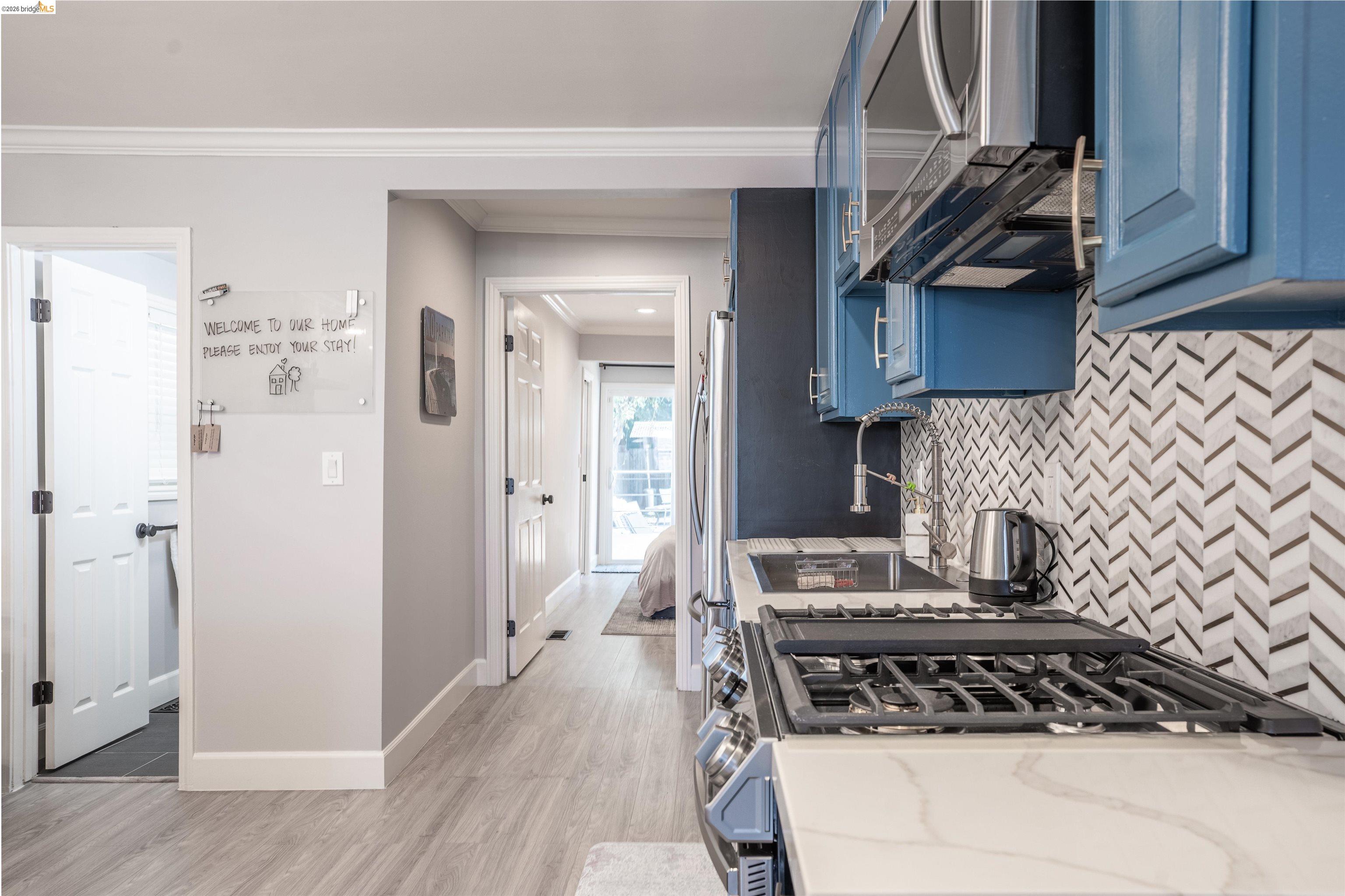 527 Chester Street Oakland, CA 94607 - Photo 10 of 47 525 (Downstairs) Kitchen featuring blue cabinets, crown molding, stainless steel appliances, light wood-style flooring, and tasteful backsplash