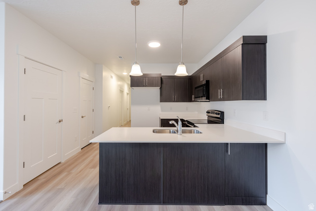 693 West 4500th South, Unit O101 Mapleton, UT 84664 - Photo 14 of 16 Kitchen with a peninsula, dark wood finish cabinetry, hanging light fixtures, stainless steel appliances, and light wood-style floors
