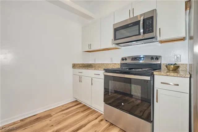 a kitchen with granite countertop cabinets stainless steel appliances and a wooden floor