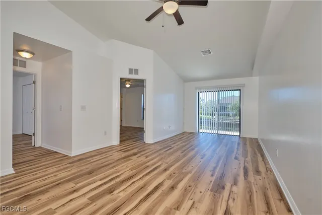 a view of an empty room with wooden floor cabinet and a window