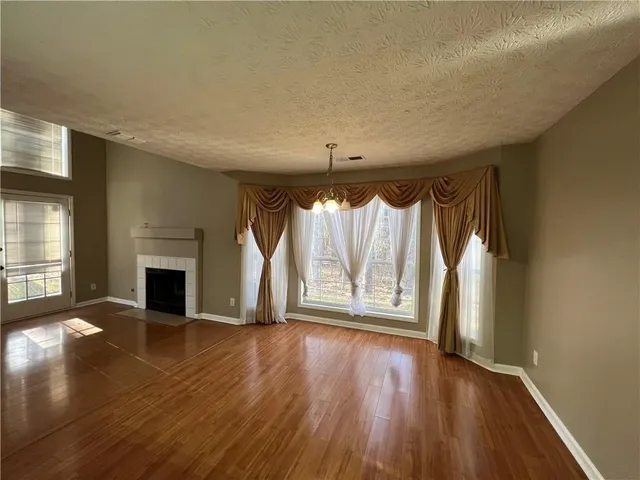 an empty room with wooden floor fireplace and windows