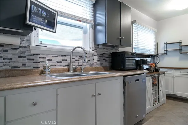 a kitchen with appliances a sink a window and cabinets