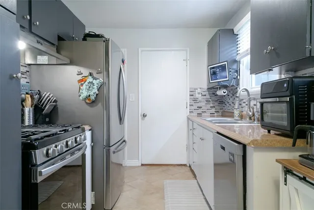 a kitchen with stainless steel appliances a sink a stove a refrigerator and cabinets