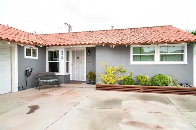 a front view of a house with a yard and potted plants