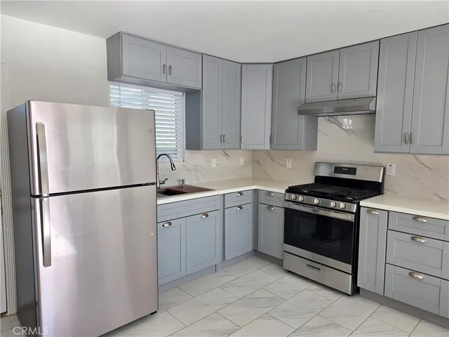 a kitchen with stainless steel appliances a sink dishwasher stove and cabinets with wooden floor