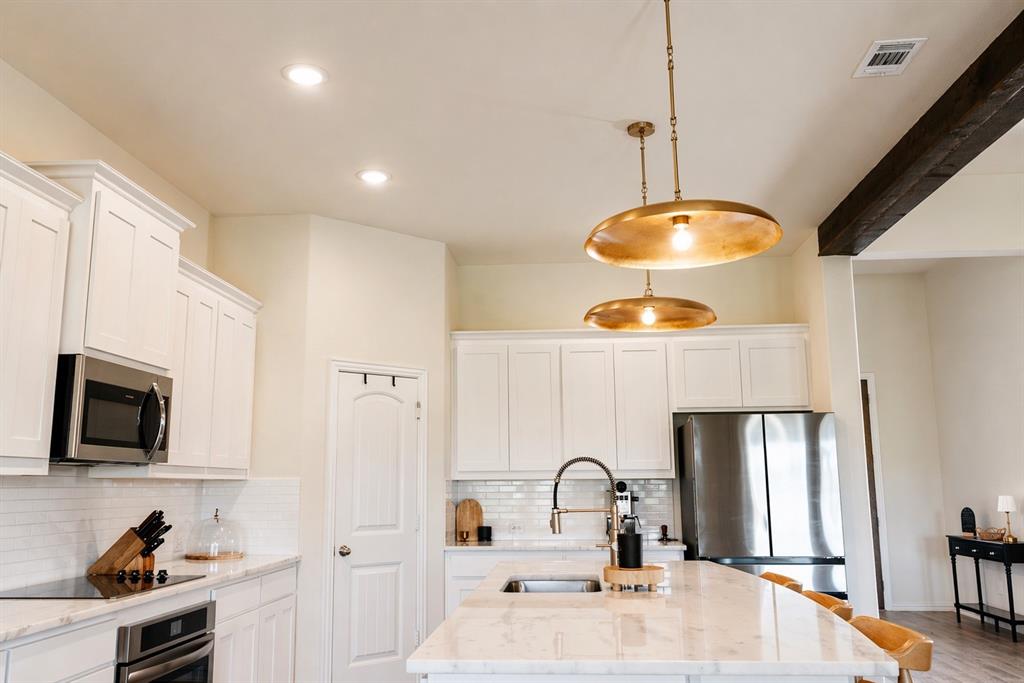 1530 County Road 200 Valley View, TX 76272 - Photo 11 of 34 Modern kitchen featuring white shaker cabinetry, stainless steel appliances, a subway tile backsplash, recessed lighting, and a kitchen island with pendant lighting
