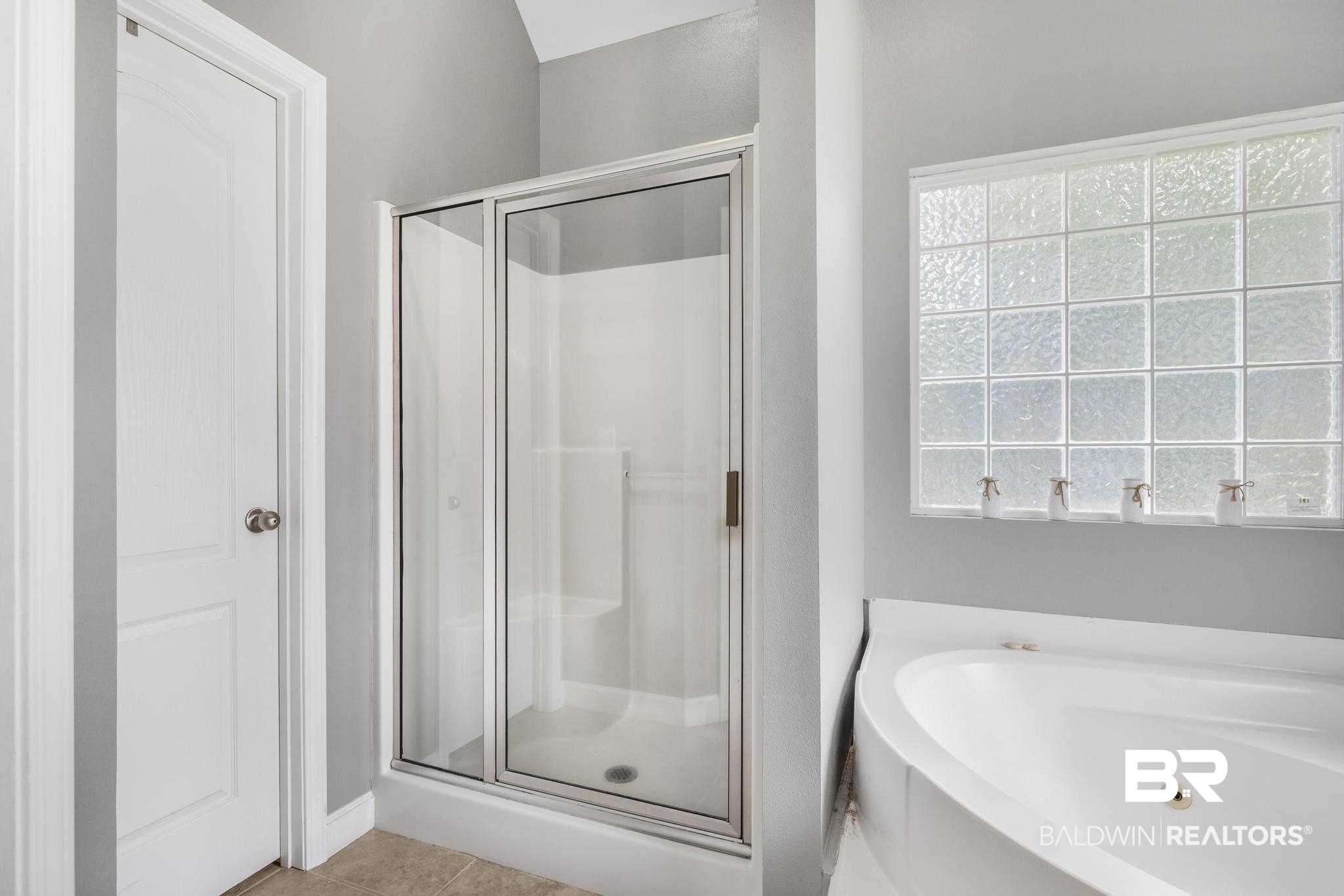 35814 Delvan Lane Bay Minette, AL 36507 - Photo 34 of 53 Spacious bathroom featuring a glass-enclosed shower, a large soaking tub, and a decorative glass block window