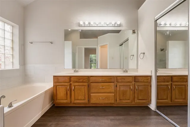 a spacious bathroom with a double vanity sink a large mirror and a bathtub