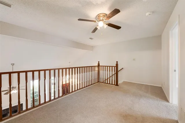 an empty room with windows and ceiling fan