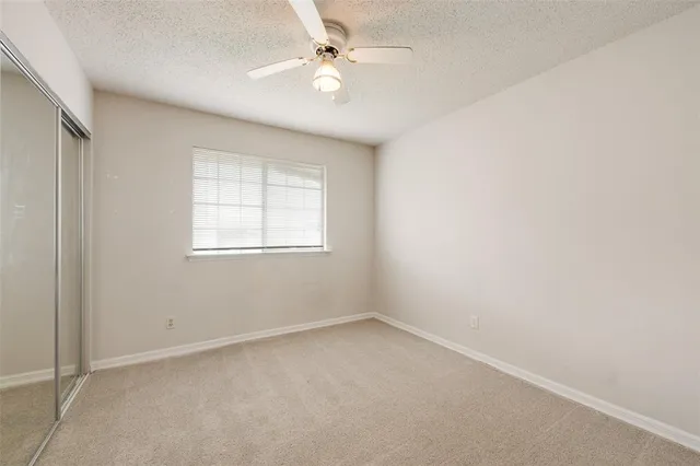 an empty room with windows and ceiling fan