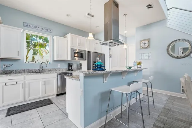 a kitchen with stainless steel appliances kitchen island granite countertop a refrigerator a stove a sink dishwasher and a dining table with wooden floor