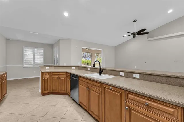 a view of an empty room with a window and kitchen view