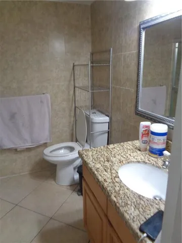 a bathroom with a granite countertop toilet and a mirror