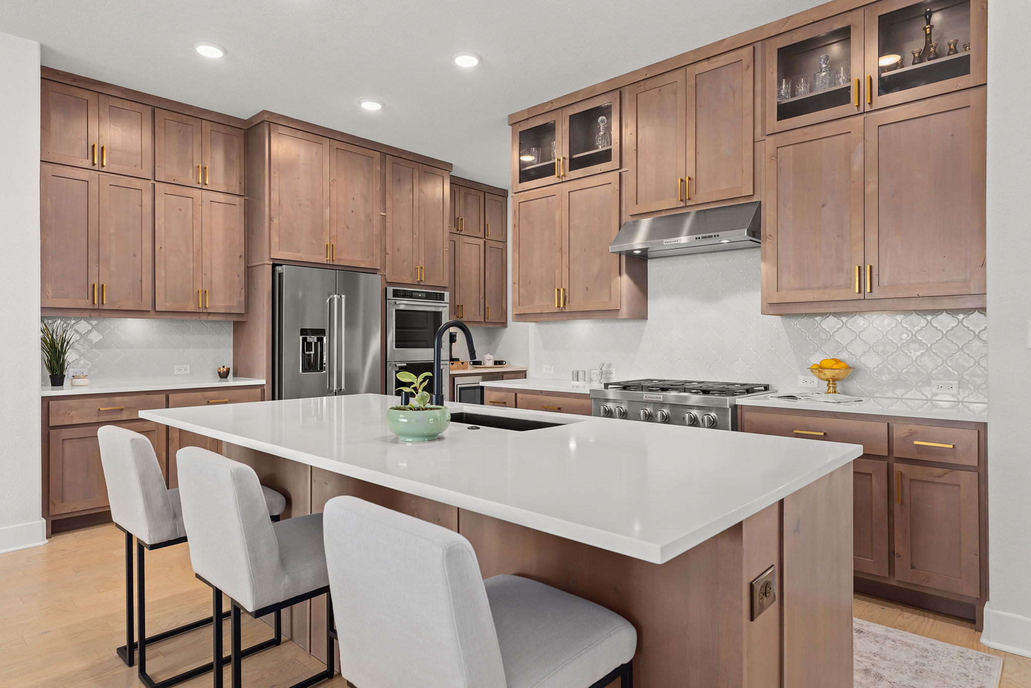 a kitchen with kitchen island a stove a refrigerator a sink a dining table and chairs