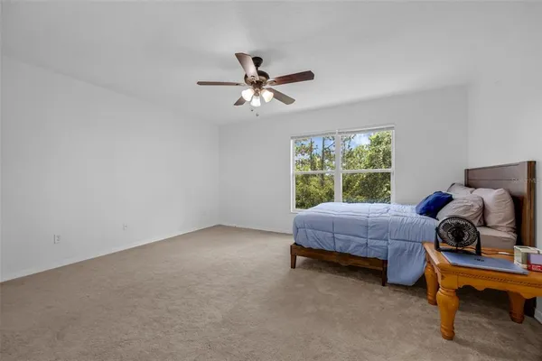 a spacious bedroom with a bed and a ceiling fan